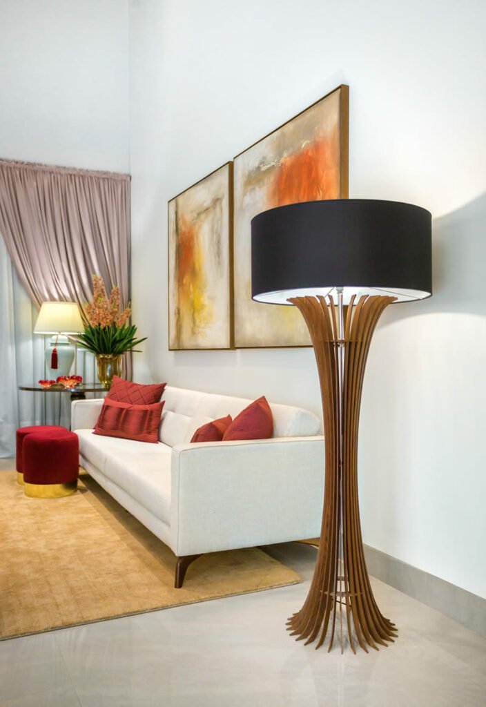 Sala de estar com quadros em parede branca e iluminação coluna Accord Stecche Di Legno ao lado de sofá