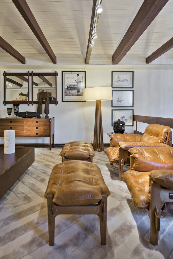Living com sofá e bancos de madeira com estofado em couro e luminária da Accord